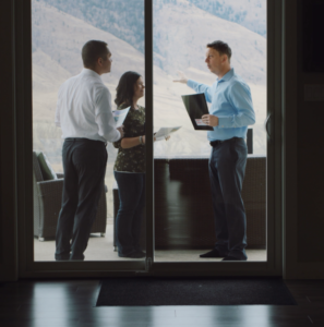 Parker talks with his clients outside on the balcony of a house during a showing